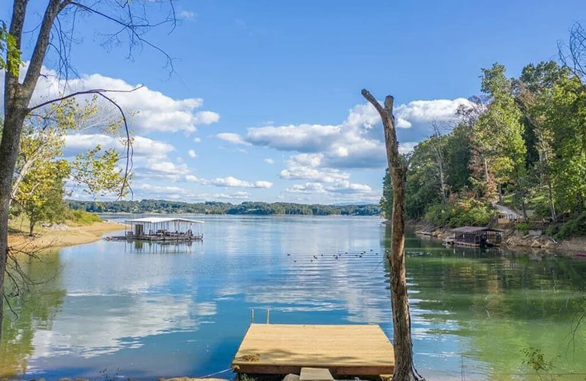 The image features a tranquil wooden dock stretching out onto calm waters, surrounded by trees and a serene sky. It evokes opportunities for fishing, boating, and wildlife watching—activities highlighted in the section. The dock underscores the theme of lakeside adventure and the changing shoreline dynamic mentioned in the content.