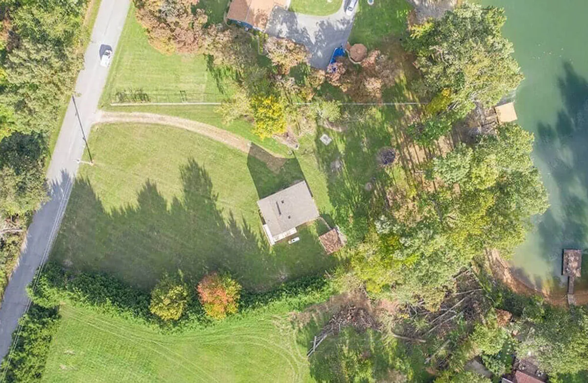 This image captures the cottage set against lush greenery with the lake visible nearby. The scene shows areas ideal for family fishing, picnicking, and general lakeside play. The spacious yard and shoreline offer a sense of openness and direct access to nature, matching the section’s emphasis on family fun and outdoor adventure.